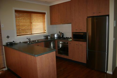 a kitchen with wooden cabinets and a stainless steel refrigerator at Villa on Nathan in Albury
