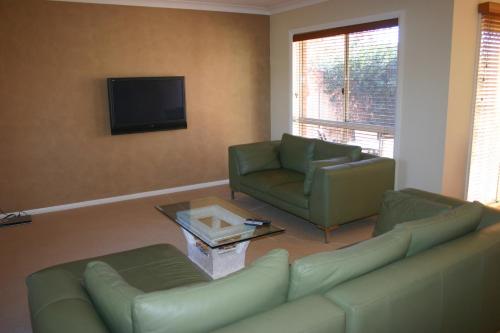 a living room with a couch and chairs and a tv at Villa on Nathan in Albury
