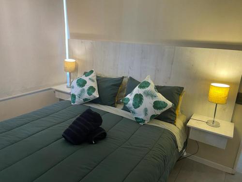 duże zielone łóżko z poduszkami i 2 lampami w obiekcie Atalaya Apartment Suite w mieście Santiago