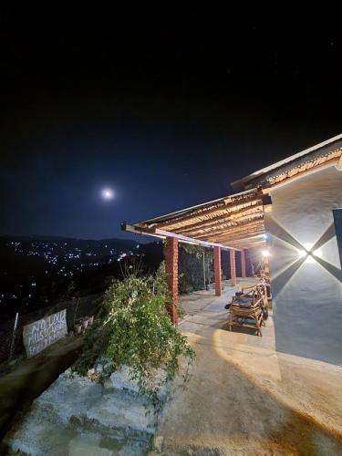 a night view of a building with the moon in the sky at Zenoaks Homestay in Almora