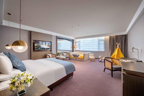 a hotel room with a bed and a living room at Novotel Nantong Center in Nantong