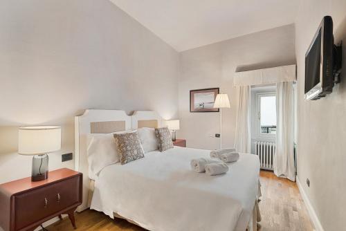 1 dormitorio con 1 cama blanca grande y TV en Tornabuoni Living - Luxury Apartments Collection en Florencia