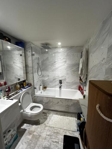 a bathroom with a tub and a toilet and a sink at Luxurious Versace Apartment in London
