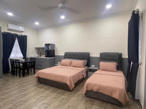 two beds in a room with a table and a kitchen at D'Laman Cottage Kota Bharu kelantan in Kota Bharu