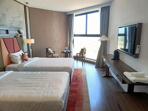 a hotel room with two beds and a television at Luxury APEC MANDALA MŨI NÉ SG HAPPY HOUSE in Ấp Thiẹn Ái