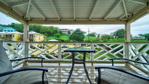 a porch with chairs and a table and a fence at Kaibus Place- Quaint Quiet and Cosy in Morne Rouge