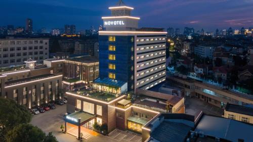 a building with a sign on top of it at night at Novotel Nantong Center in Nantong