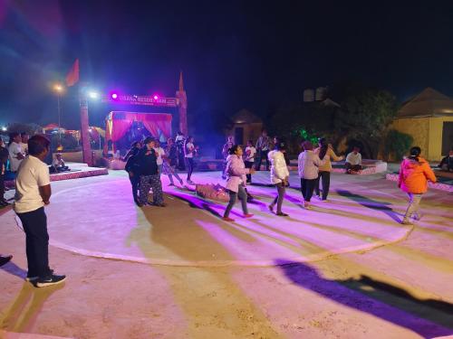 un groupe de personnes dansant sur une scène la nuit dans l'établissement Awar Desert Safari, à Jaisalmer
