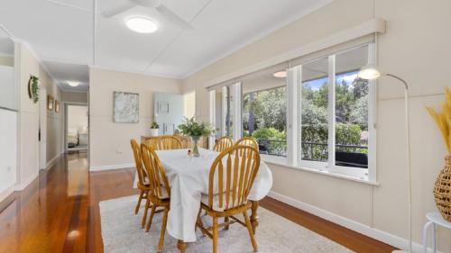 a dining room with a table and chairs and windows at Kooringal Cottage - Home By The Sea in Woorim