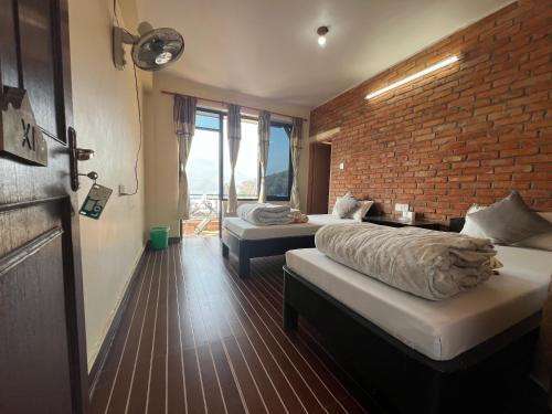 a bedroom with two beds and a brick wall at Little Pilgrim Family Lodge in Pokhara