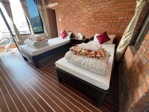 two beds in a room with a brick wall at Little Pilgrim Family Lodge in Pokhara