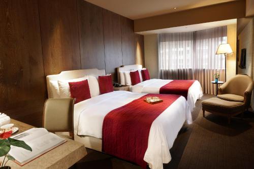 a hotel room with two beds with red and white sheets at Palais de Chine Hotel in Taipei