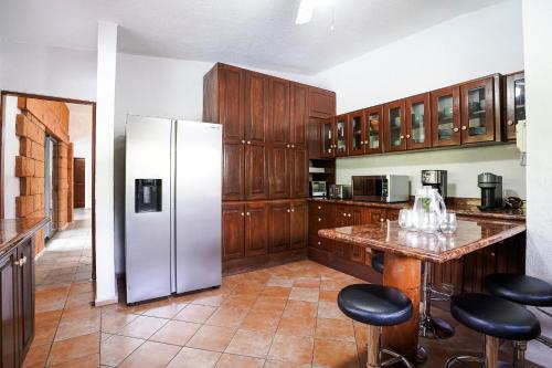 a kitchen with a refrigerator and some bar stools at Cozy family house I Pool & Bar l Cuernavaca in Cuernavaca