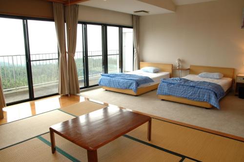 a bedroom with two beds and a coffee table andwindows at Mt.Fuji Rising Sun Inn in Fuji