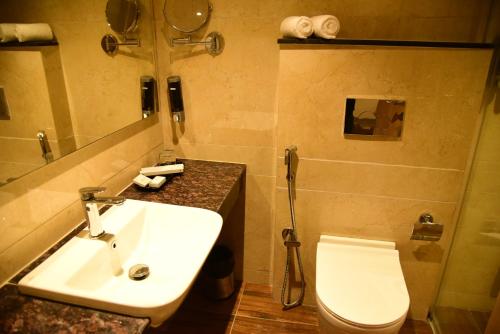 ein Badezimmer mit einem weißen Waschbecken und einem WC in der Unterkunft Hotel Grand Serene, Mysore in Mysore