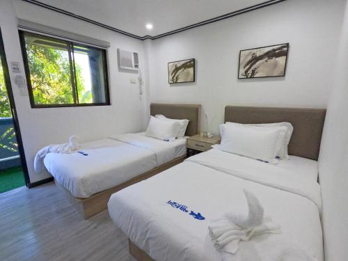 a hotel room with two beds and a window at Lucky Tito Coron Dive Resort in Coron
