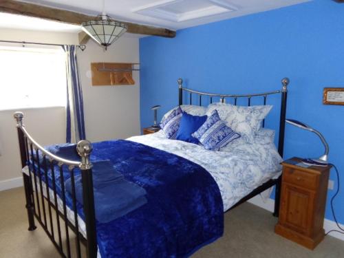 a blue bedroom with a bed with a blue comforter at Lodge House B&B in Buckland St Mary