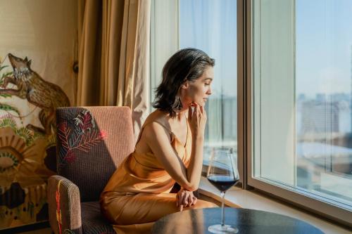 une femme assise à une table avec un verre de vin dans l'établissement Park Hotel Tokyo, à Tokyo