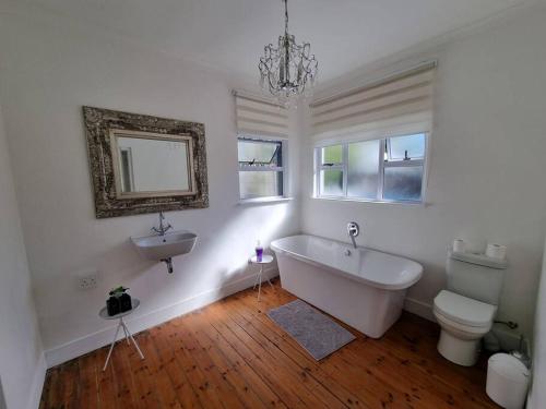 a white bathroom with a tub and a sink at Cottage at 6 on Elba in Paarl