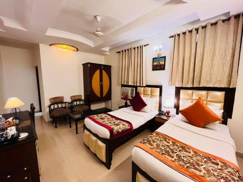 a hotel room with two beds and a living room at Paras Inn in New Delhi