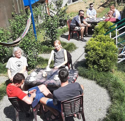 a group of people sitting around a table in a garden at Little Pilgrim Family Lodge in Pokhara