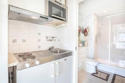 cocina blanca con lavabo y aseo en Cosy and functional Studio in London en Colindale