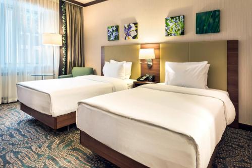 a hotel room with two beds and a desk at Hilton Garden Inn Astana in Astana