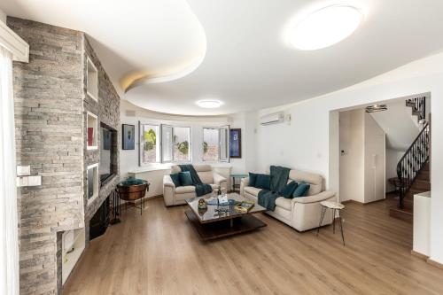 a living room with white furniture and a brick wall at Accomoteleia Crystal Lagoon Villa in Protaras