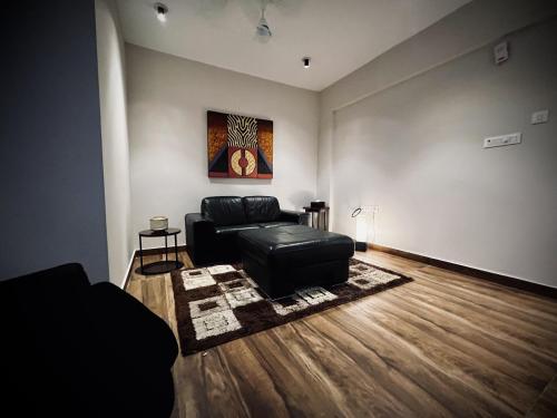 uma sala de estar com um sofá de couro preto e um quadro em King Suite Luxury 74 sqm em Madurai
