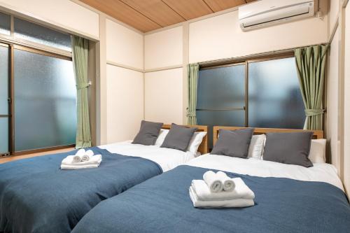 two beds with towels on them in a bedroom at 神谷戸建 in Tokyo