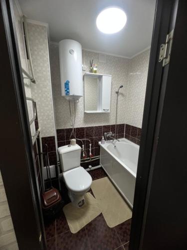 a bathroom with a toilet and a sink and a tub at Однокомнатная квартира in Balqash