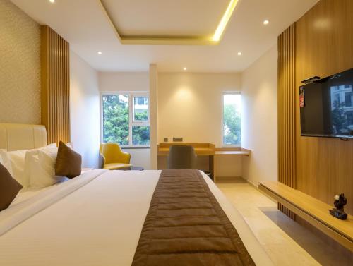Pokój hotelowy z dużym łóżkiem i telewizorem w obiekcie Hotel Grand Serene, Mysore w mieście Mysuru