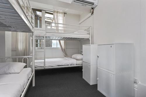 a room with two bunk beds and a refrigerator at Serene Hostels in Sydney