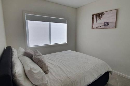 a white bedroom with a bed with a window at 1/84 in Panania