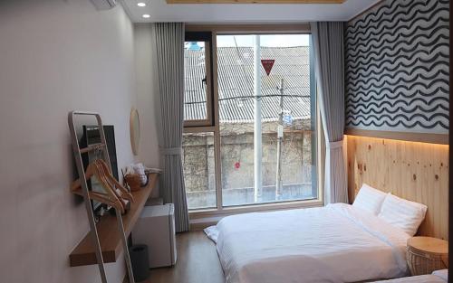 a bedroom with a bed and a large window at 38th Street Guesthouse in Mokpo