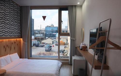 1 dormitorio con cama y ventana grande en 38th Street Guesthouse en Mokpo