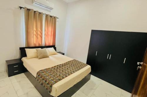 LES 9 Plurielles T3 KPALIME KOUMA KONDA في Kpalimé: غرفة نوم مع سرير كبير مع اللوح الأمامي الأسود