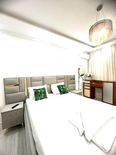 a bedroom with a large white bed and a desk at Уютные апартаменты в самом центре города на площади Исатая Махамбета in Atyraū