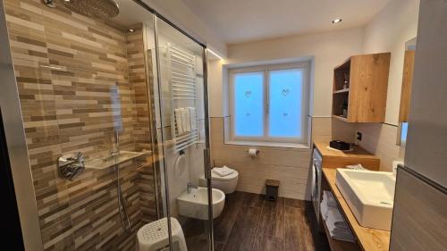 a bathroom with a shower and a toilet and a sink at Casa Il Giardino in Pozza di Fassa