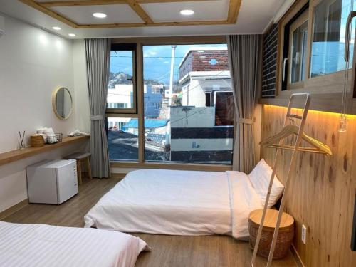 a bedroom with two beds and a large window at 38th Street Guesthouse in Mokpo