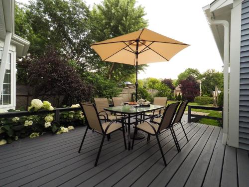 a table with chairs and an umbrella on a deck at Blue Skies Bed & Breakfast in Niagara-on-the-Lake