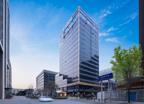 a tall glass office building in a city at Shenzhen Zhongchen International Hotel - Shenzhen Baolong Subway Station Branch in Shenzhen