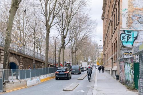 een persoon op een fiets door een straat met auto's bij Chic Studio Apartment for 3 - La Villette! in Parijs