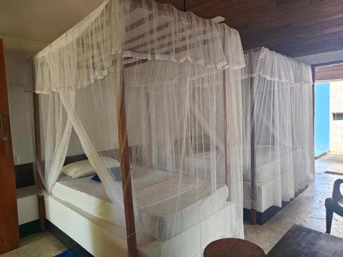 a bedroom with a canopy bed with white curtains at Bella Nilaveli Beach in Nilaveli