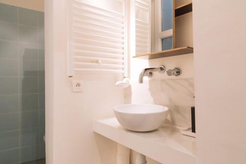 La salle de bains est pourvue d'un lavabo blanc sur un comptoir. dans l'établissement Cosy & Stylish Large Studio VoltaireOberkampf!, à Paris