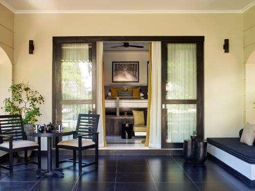 a living room with a table and chairs and a piano at Sun Siyam Pasikudah in Pasikuda