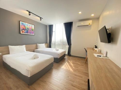 um quarto de hotel com duas camas e uma televisão de ecrã plano em โรงแรม เดอะโมเดล การ์เด้น em Yasothon