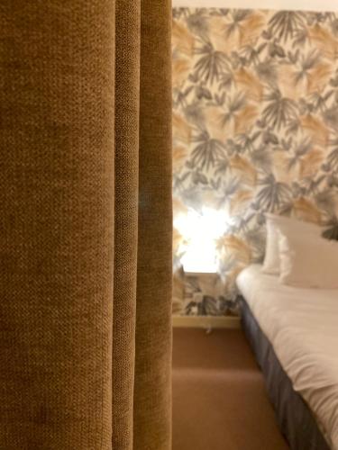 a room with a bed and a curtain and a lamp at Logis Hôtel Médiéval, Montélimar Nord in Rochemaure