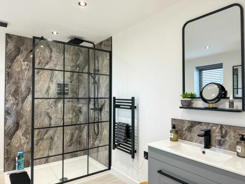 a bathroom with a shower with a sink and a mirror at Brooke View Barns No 1 in Norwich