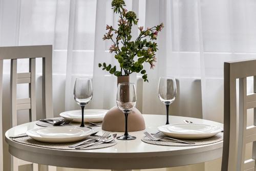a table with plates and glasses and a vase with flowers at Sika DeLuxe Apartment Arad in Arad